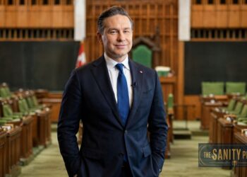 A man in a navy suit stands smiling in the center aisle of an empty parliamentary chamber with green seats. A Canadian flag is visible behind him, and “The Sanity Project” logo appears in the lower right—Pierre Poilievre is pictured.